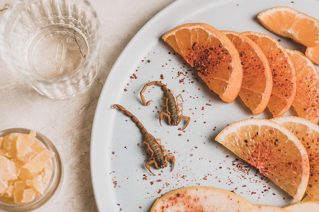 Scorpions and Oranges with Spices on a White Plate Next to a Glass and Jar of Candy